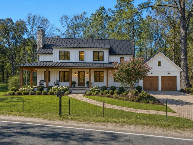 The same lot with a white two-story farmhouse, wraparound porch, garage and new landscaping in place of the trailer and trucks